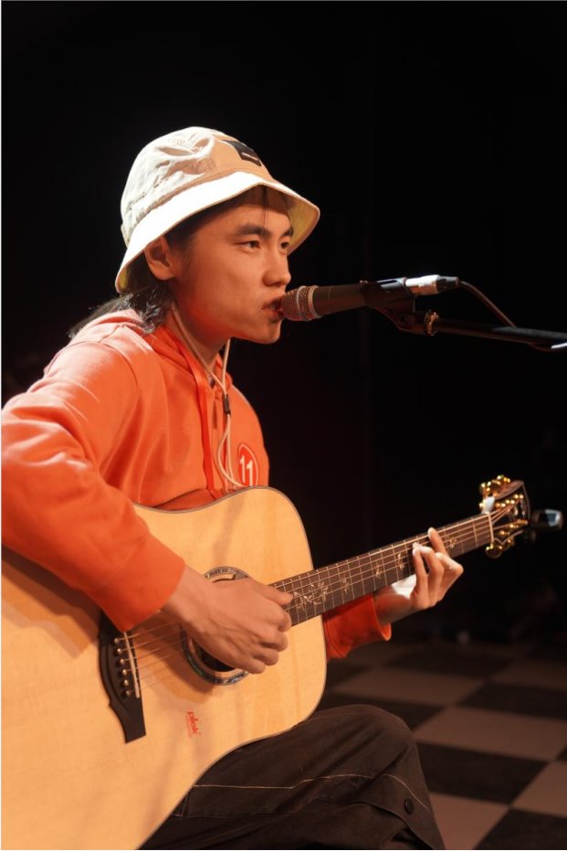 Close-up of a contestant singing and playing guitar